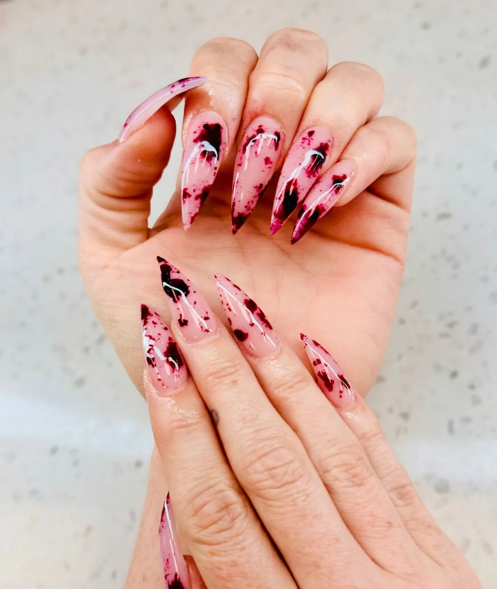 Extra long sheer pink stiletto nails with a dark cherry red marble design by Hailey Nguyen